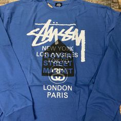 Get ready to add some 🔥 to your wardrobe with the Stussy X Dover Street Market DSM World Tour LS Tee Shirt Mens! Made from 100% cotton, this collaboration piece features long sleeves for extra coverage and style. Perfect for any casual occasion, it's the ultimate must-have for any Stussy fans. Long Sleeve Text Print Shirt For Streetwear, Long Sleeve Shirt With Text Print For Streetwear, Text Print Long Sleeve Shirt For Streetwear, Blue Shirt For Streetwear In Fall, Urban Long Sleeve Tops With Logo Print, Blue T-shirt For Fall Streetwear, Urban Blue Tops With Text Print, Urban Style Long Sleeve Letter Print Tops, Urban Style Long Sleeve Tops With Letter Print