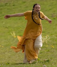 a woman is running in the grass with her arms outstretched