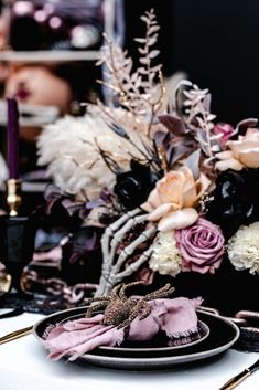 the table is set with black and white plates, silverware, and purple flowers