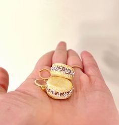 a hand holding two miniature donuts with sprinkles