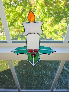 a stained glass candle is on the window sill