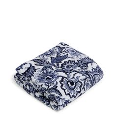 the blue and white floral print blanket is folded on top of a white tablecloth