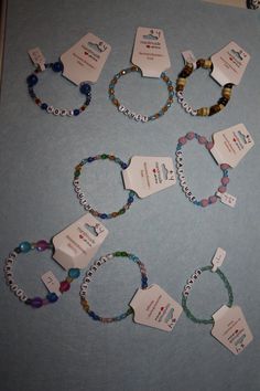 several bracelets with name tags attached to them on a blue tablecloth covered surface