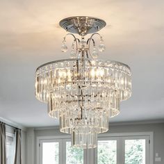 a crystal chandelier hanging from the ceiling in a room with white walls and windows