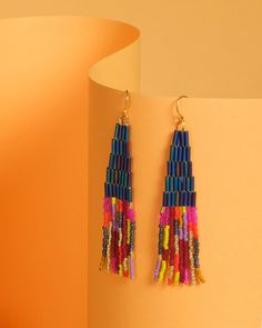 Lightweight, colorful, and unique these handwoven Japanese glass beaded earrings combine tubular beads with classic smaller beads for contrast. The hand strung fringe is made up of beautiful bead colors including gold for a touch of shimmer, which are organized in abstract lines. The beaded portion of the earring is hung from a hypoallergenic 14K gold plated ear wire. These earrings are designed by myself and made in conjunction with my team of women artisans from vulnerable communities in Medel Gold Heishi Beaded Earrings With Colorful Beads, Gold Heishi Bead Earrings With Colorful Beads, Multicolor Beaded Tassel Earrings For Party, Colorful Heishi Beaded Dangle Earrings, Colorful Heishi Bead Dangle Earrings, Multicolor Beads With Beaded Fringe For Jewelry Making, Multicolor Beaded Fringe Earrings For Party, Multicolor Dangle Beaded Earrings With Gold Beads, Multicolor Heishi Beads Jewelry With Dangling Beads