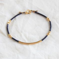 This navy and gold bracelet is stackable and wonderful for everyday wear.   D E T A I L S *14kt gold filled tube  *Tiny seed beads *14kt gold filled and plated accents  *Optional extender to fit up to a 7.5 inch wrist  Hand strung on beige silk string  ∙ EXTRA LOVE ∙ Handcrafted just for you in sunny Arizona by a team of talented women. All of our jewelry comes gift packaged! We are happy to leave a note if this is a special gift, just let us know in the message box at checkout. PRODUCTION ∙ TIMES All items are made to order. Please check the estimated delivery in the shipping section for the most current production time. If you need it sooner, select a faster shipping at checkout. All designs & content © The Silver Wren Adjustable Minimalist Gold Bracelet Hand-strung, Adjustable Minimalist Hand-strung Gold Bracelet, Dainty Hand-wrapped Gold Beaded Bracelets, Minimalist Adjustable Hand-strung Gold Bracelet, Dainty Hand Wrapped Gold Beaded Bracelets, Gold Bohemian Friendship Bracelets For Everyday, Bohemian Gold Friendship Bracelets For Everyday, Everyday Gold Bohemian Friendship Bracelets, Minimalist Gold Beaded Bracelets Hand Wrapped