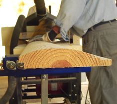 a man working on a piece of wood that is being cut in half with a planer