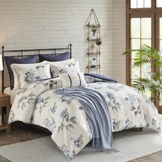 a bed with blue and white comforters in a room next to a window,