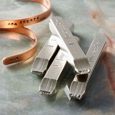 three pieces of metal sitting on top of a table next to a bracelet that says i am great