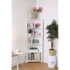 a white book shelf with flowers and books on it in the corner of a room