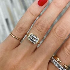 a woman's hand with three different rings on her fingers and one is wearing a red manicure