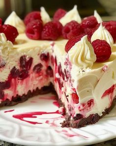 a white plate topped with a cheesecake covered in raspberries