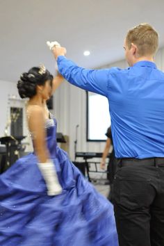 a man standing next to a woman in a blue dress on top of a dance floor