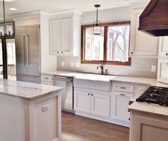 a large kitchen with white cabinets and an island in the middle is shown, along with stainless steel appliances