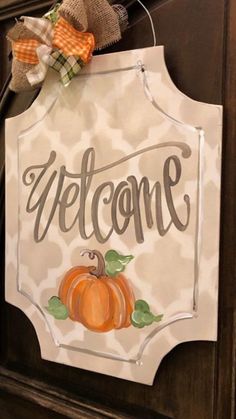 a welcome sign hanging from the side of a wooden door with a pumpkin on it