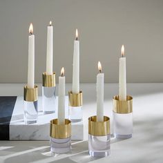 five white candles with gold rims are lined up next to each other on a marble block