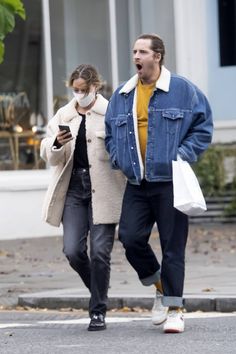 a man and woman walking down the street while wearing face coverings on their faces