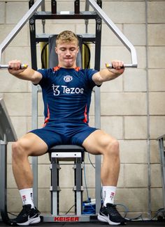 a man sitting on top of a bench holding a barbell