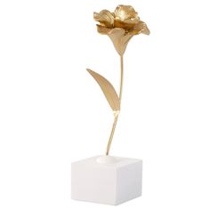 a white vase with a gold flower in it's center on a white surface