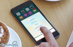 a person touching the screen on their cell phone at a table with coffee and donuts