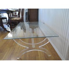 a glass table with metal legs on a wooden floor