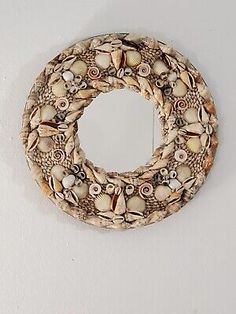 a circular mirror hanging on the wall next to a white wall with shells and seashells