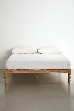 a bed with two pillows on top of it in a white walled room next to a wall