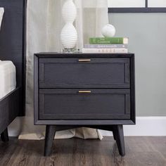 a night stand with two drawers in front of a white curtain and a black headboard