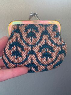 a hand holding a small purse with blue and brown designs on it's side