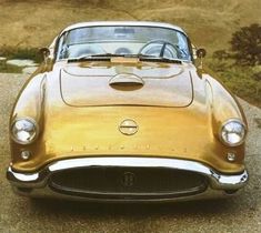 an old gold sports car is parked on the road