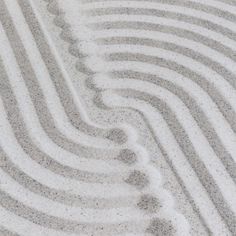 the sand has wavy lines drawn on it and is white with gray dots around it