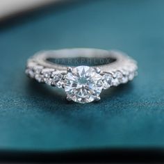 an engagement ring with three diamonds on it sitting on top of a blue velvet surface