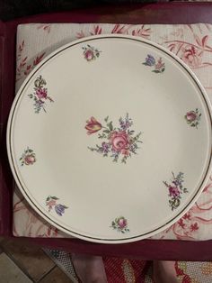 a white plate with pink and purple flowers on it sitting on top of a table