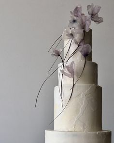 a three tiered white cake with purple flowers on top