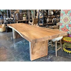 a large wooden table sitting on top of a floor next to other chairs and vases