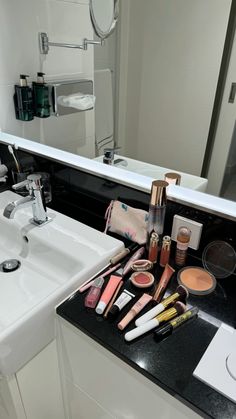 a bathroom sink with makeup and cosmetics on it