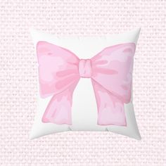 a pillow with a pink bow on the front and back of it, against a light pink background