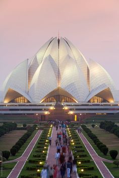 people walking in front of the lotus shaped building at dusk by luke walker for stockstuffs