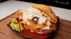 a fried chicken sandwich on a red plate with sour cream and avocado wedges