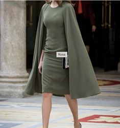 a woman in a green dress and coat