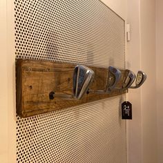 a wooden wall mounted with five different types of scissors on it's side and a metal hook in the middle