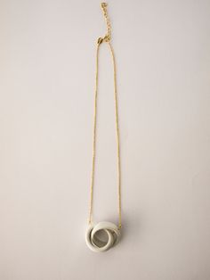 a necklace with an oval shaped pendant hanging from a gold chain on a white surface