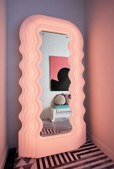 a large pink mirror sitting in the corner of a room