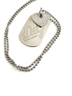 VINTAGE DOLCE GABBANA NECKLACE  Silver metal base with big panel signes D&C and Dolce Gabbana ,top on panel Rhinestone heart This necklace is beautiful cond and its priced to sell  ca 1980s D&G. Chain 22 inc long  Panel 1,5 inc long 1,1 inc wide. Vintage Silver Dog Tag Necklace, Vintage Silver Necklace With Logo Charm, Year 2, Rhinestone Heart, Dog Tag, Locket Necklace, Dolce & Gabbana, Metal Base, Necklace Silver