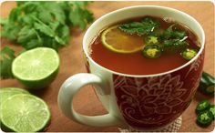 a cup filled with soup and garnish next to limes