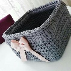 two gray baskets with pink bows on them sitting on a white table next to a purple pillow