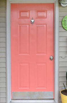 a pink front door on a house with potted cacti and succulents