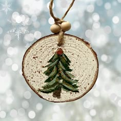 a wooden ornament with a christmas tree on it hanging from a string and snowflakes in the background