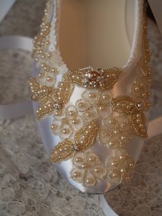 a pair of white shoes with pearls on them