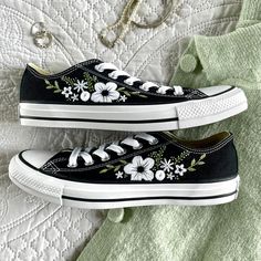 black and white shoes with flowers painted on them sitting on a quilted bed spread